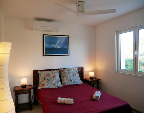 a bedroom with a bed with red sheets and two lamps at Bel appartement 3 pièces en villa climatisé 800m plage WIFI in Cavalaire-sur-Mer