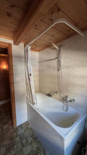 a bath tub in a room with a wooden ceiling at Müllerhus in Kandersteg