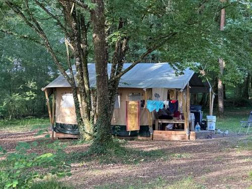 une tente dans un champ à côté d'un arbre dans l'établissement Camping du Bas Meygnaud, à Lasserre