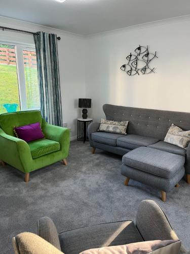 a living room with a couch and a green chair at Stylish Highland Home in Fort William
