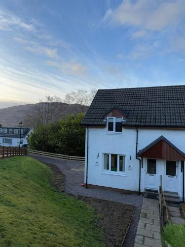 a white house with a black roof and a yard at Stylish Highland Home in Fort William