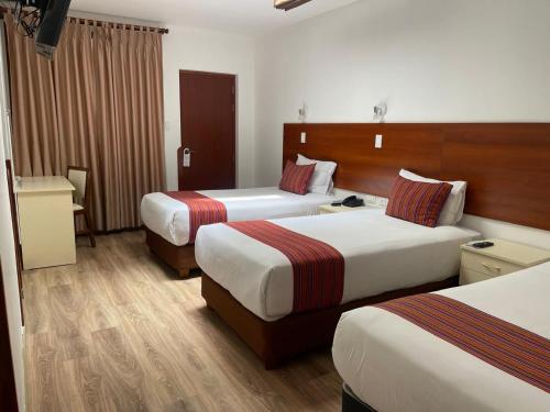 a hotel room with two beds and a desk at Hotel San Pedro Plaza in Cusco