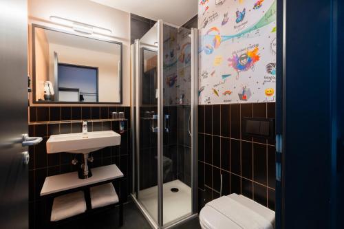 a bathroom with a shower and a sink and a toilet at Holiday Inn - the niu, Blade Solingen by IHG in Solingen