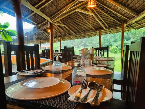a wooden table with plates and utensils on it at Lekker Gezellig Dive Resort Manado in Bunaken
