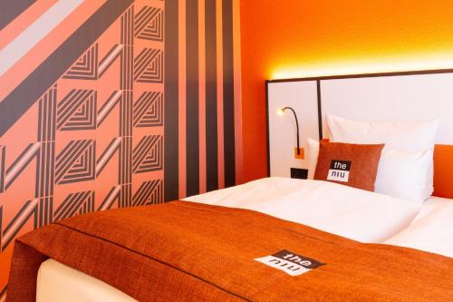 a hotel room with a bed with an orange wall at Holiday Inn - the niu, Blade Solingen by IHG in Solingen