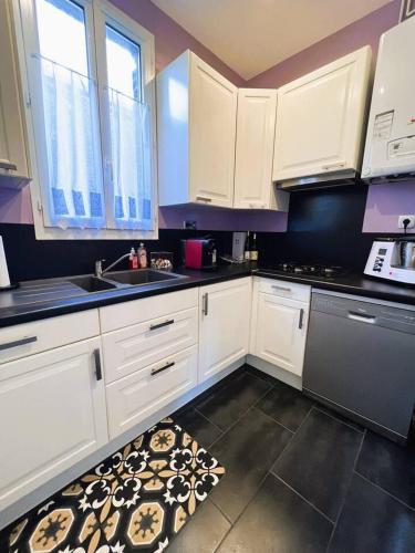 - une cuisine avec des placards blancs, un évier et un tapis dans l'établissement Appartement Marceau, à Mers-les-Bains