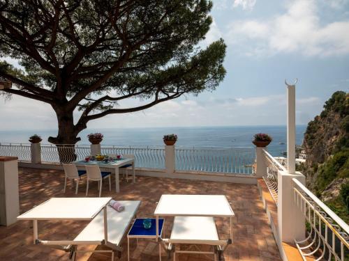 a balcony with tables and a tree and the ocean at Villa Cliff House - Casa Dominique in Ravello
