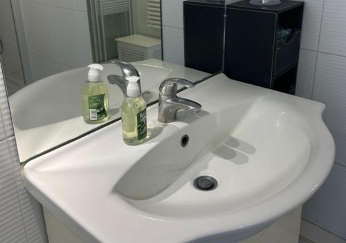 - un lavabo blanc dans la salle de bains avec 2 bouteilles dans l'établissement Loft Le Marais à Place des Vosges, à Paris