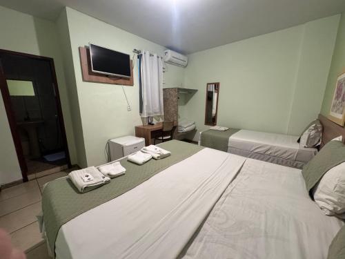 a hotel room with two beds and a television at Domus Hotel Veneza - Ipatinga in Ipatinga