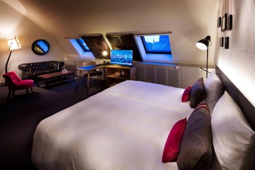 a bedroom with a large white bed and a desk with a computer at pentahotel Leuven in Leuven