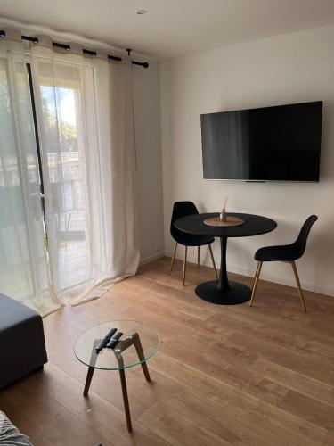 - un salon avec une table, des chaises et une télévision dans l'établissement Charmant Studio à Ajaccio, à Ajaccio