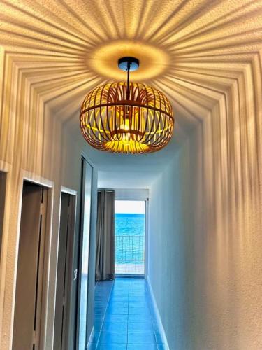 - un couloir avec un plafond orné d'un lustre dans l'établissement Face à la mer, au Barcarès