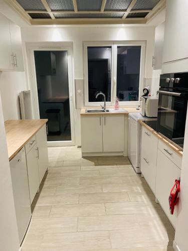 une cuisine avec des armoires blanches et un sol carrelé dans l'établissement Maison centre ville, à Calais