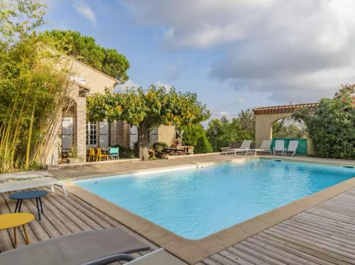 une piscine avec une terrasse en bois à côté d'une maison dans l'établissement La Bastide de la Nîmes, à Nîmes