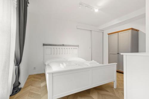 a white bedroom with a white bed and a refrigerator at Rustic Vineyard House in Modra