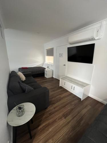 a living room with a couch and a flat screen tv at Almond Inn Motel in Tamworth