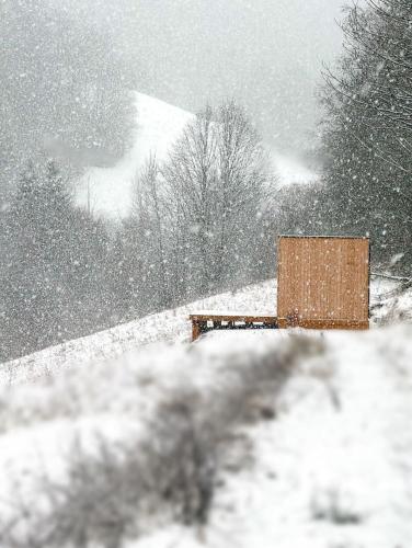 a wooden bench in a snow covered field at Domček Lazy in Lazy pod Makytou