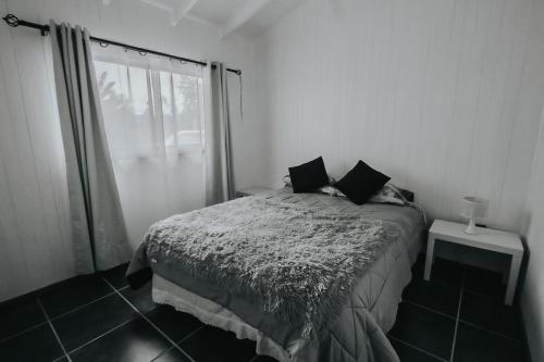 a white bedroom with a bed and a window at Cabañas Altos del Volcán in Villarrica