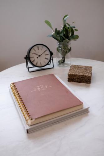 a notebook sitting on a table with a clock at Charming Hoover Hideaway - Studio - A Location in Joshua Tree
