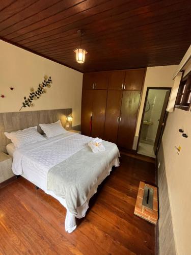 a bedroom with a large white bed with wooden floors at Recanto dos Vianas in Teresópolis