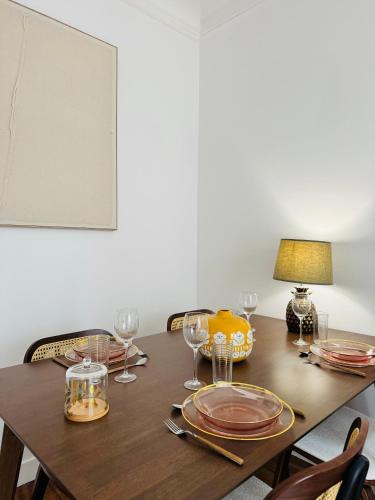 une table en bois avec des assiettes et des verres à vin dessus dans l'établissement Luxueux 2 pièces au cœur du 16e, à Paris