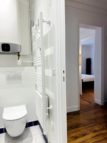 - une salle de bains blanche avec toilettes et une chambre dans l'établissement Luxueux 2 pièces au cœur du 16e, à Paris