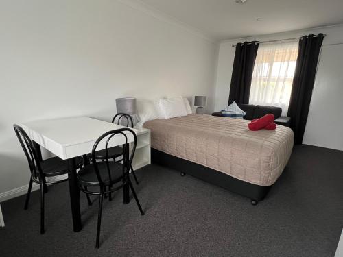 a bedroom with a bed and a table with chairs at Almond Inn Motel in Tamworth