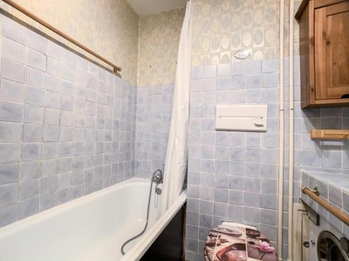 La salle de bains est pourvue de carrelage bleu, d'une baignoire et d'un lavabo. dans l'établissement Résidence Grandes Platieres 2 - Studio cabine situé dans le centre du Val Claret MAE-2324, à Tignes