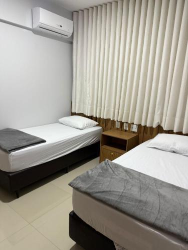 a bedroom with two beds and a window with curtains at Apartamento bem localizado perto de tudo - 3 quartos em Belém in Belém