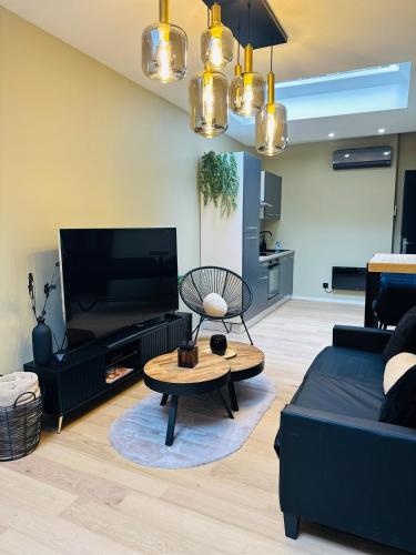 a living room with a black couch and a table at Élégant appartement avec bain balnéothérapie in Liège