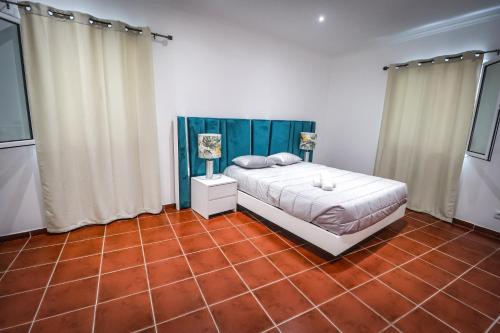 a bedroom with a bed and a red tile floor at Casa do Parque in Rabo de Peixe