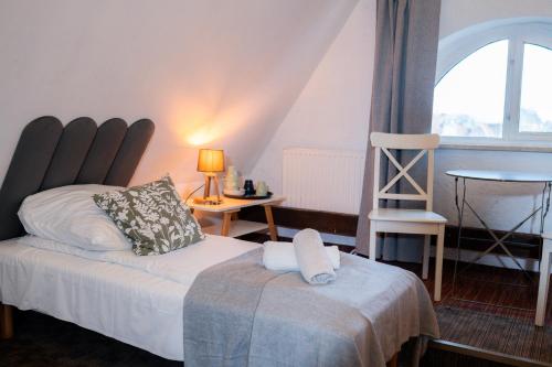 a bedroom with a bed and a chair and a window at Dom Zachariasza Zappio in Gdańsk