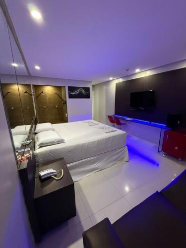 a bedroom with a large bed and a tv at Tititi Motel in Olinda