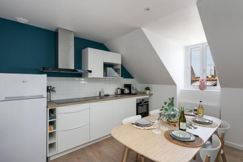 une cuisine avec une table et un réfrigérateur blanc dans l'établissement Appartement Le Cap Morgat, à Crozon