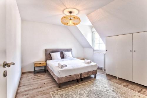 - une chambre blanche avec un lit et un lustre dans l'établissement Villa Kdo 4 chambres CLS Deauville, à Deauville