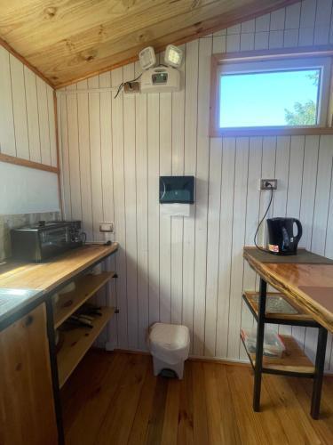 a small kitchen with wooden counters and a window at Bauda Cabaña Costera in Cochamó