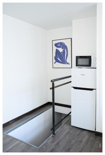 Il comprend une cuisine blanche équipée d'un four micro-ondes et d'un réfrigérateur. dans l'établissement 2 pièces à 10 minutes de Paris, à Ivry-sur-Seine