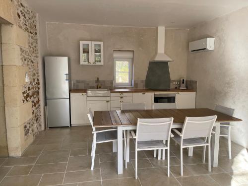- une cuisine avec une table en bois et des chaises blanches dans l'établissement Le domaine du Martinet, à Salles