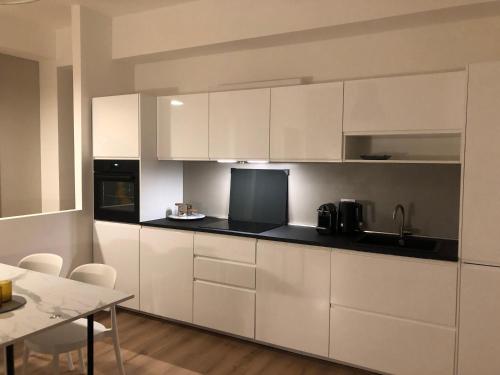a kitchen with white cabinets and a dining table at Verde Acqua Suite in Lecco