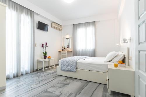 a white bedroom with a bed and a window at Azur Playa Naxos in Naxos Chora