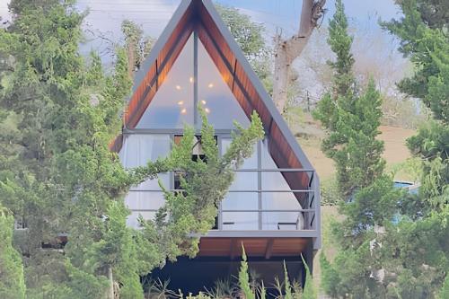 a house with a triangular roof with glass windows at Pousada Casa Florinda in Teresópolis