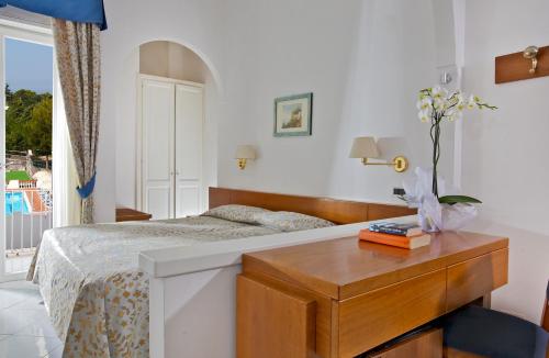 a bedroom with a bed and a table and a window at Hotel San Michele in Anacapri