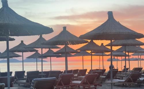 a group of chairs and umbrellas on a beach at ELMAR COMFORT in Vlorë