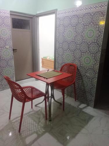 a red table and two chairs in a room at hay nour in Benguerir