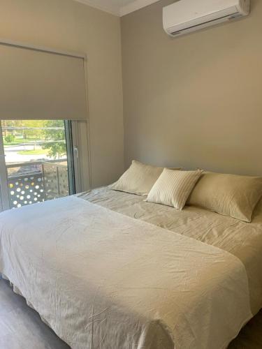 Un dormitorio con una cama blanca con una ventana. en Laprida Suites 1 San Juan, en San Juan