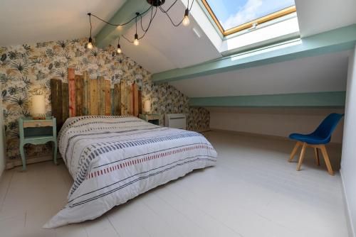 a bedroom with a bed and a blue chair at La Maison de la Plage in Le Grau-du-Roi