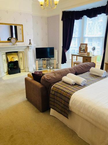 a bedroom with a bed and a couch and a tv at The Pathway Guesthouse in Whitby