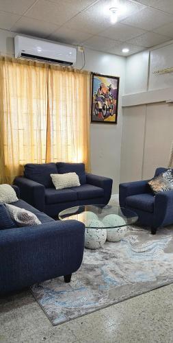 Una sala de estar con sofás azules y una mesa. en The M4 Elegant 3 bedroom home in Port of Spain, en Puerto España