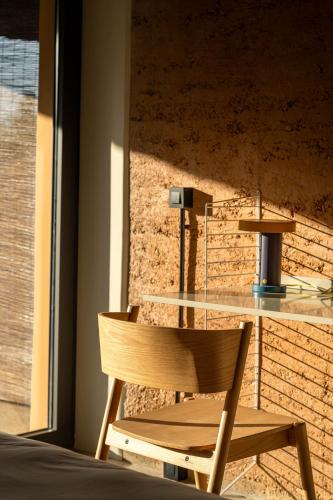 a glass table and a wooden chair in a room at Gandum Village - Conscious Boutique Hotel in Montemor-o-Novo