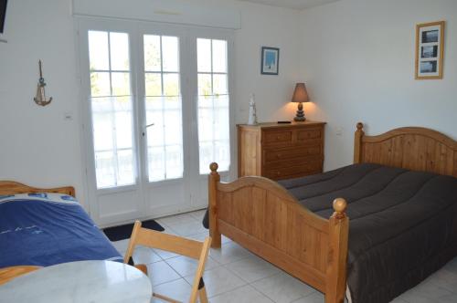 um quarto com uma cama, uma cómoda e janelas em L'Escale de la Baie de Somme em Le Crotoy